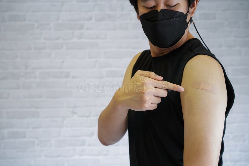 接受covid19疫苗注射后，年轻接种疫苗的男子用贴膏绷带放手臂