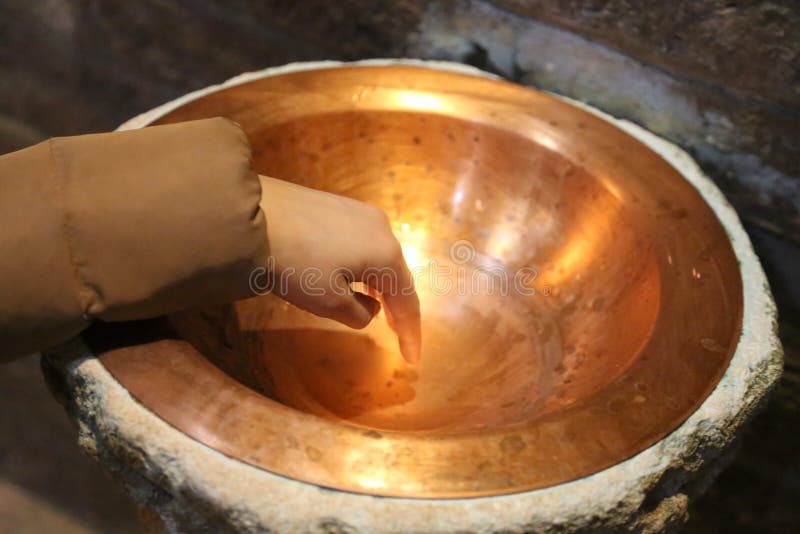 接触在ancien的字体stoup的孩子的手水 库存图片