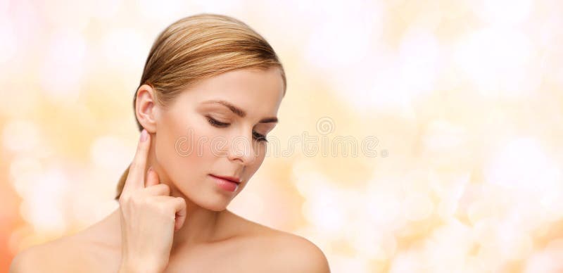 Health and beauty concept - face of beautiful woman touching her ear. Health and beauty concept - face of beautiful woman touching her ear