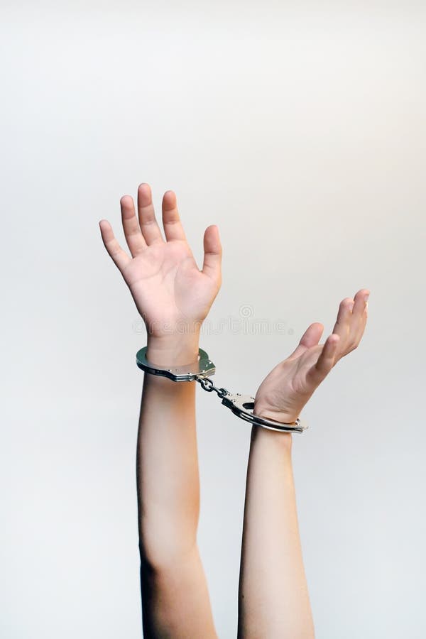 Arrested woman handcuffed hands. Prisoner or arrested terrorist, close-up of hands in handcuffs isolated on brown background. Criminal female hands locked in handcuffs. Close-up view. Arrested woman handcuffed hands. Prisoner or arrested terrorist, close-up of hands in handcuffs isolated on brown background. Criminal female hands locked in handcuffs. Close-up view