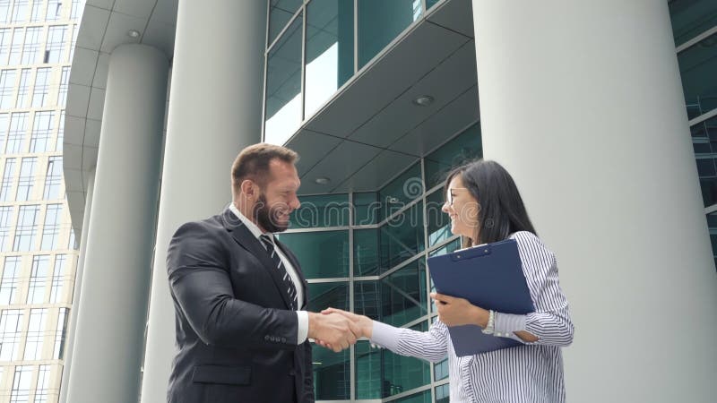 握手的两个商人男人和妇女户外在商业中心附近