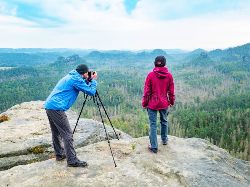 摄影师在三脚架上检查摄像机取景器并框定自然场景