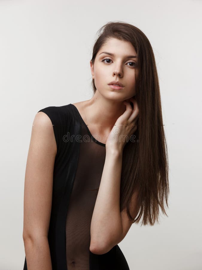 摄影棚中一位时尚女模特的垂直画像,身穿黑色健身衣,在白色背景中 免版税库存照片 摄影棚中一位时尚女模特的垂直画像,身穿黑色健身衣,在白色背景中 免版税库存照片