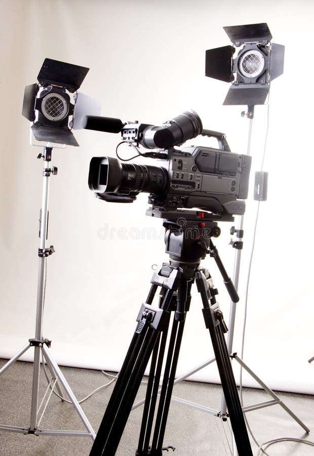 Black dv camera recorder on tripod and two spot lights in the studio. Black dv camera recorder on tripod and two spot lights in the studio