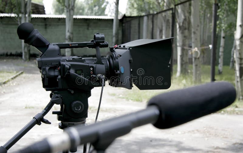 Stand high definition camcorder on nature shooting and studio microphone in bluring front. Stand high definition camcorder on nature shooting and studio microphone in bluring front