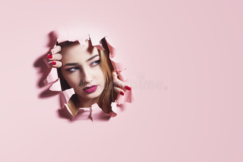 撕毁在桃红色纸板纸,一个女孩的面孔的年轻女人的时尚画象一个孔有构成的,创造性的概念 免版税库存照片 撕毁在桃红色纸板纸,一个女孩的面孔的年轻女人的时尚画象一个孔有构成的,创造性的概念 免版税库存照片