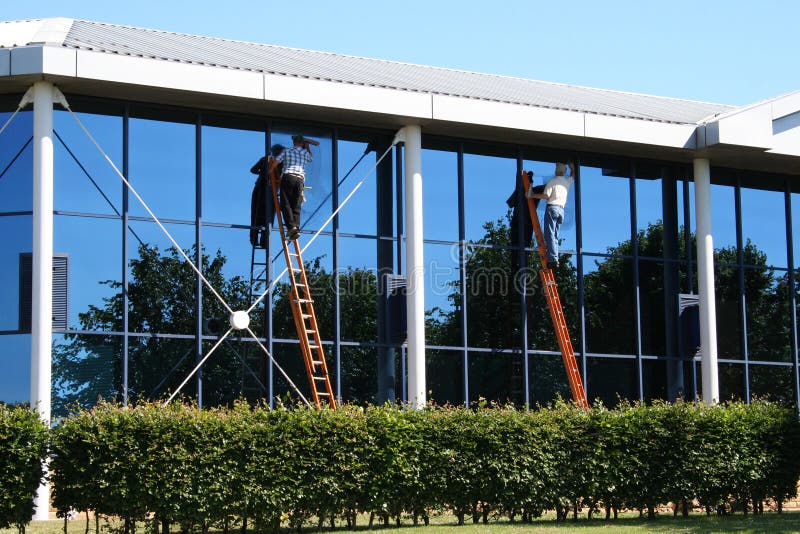 Two window cleaners at work on office building. Two window cleaners at work on office building