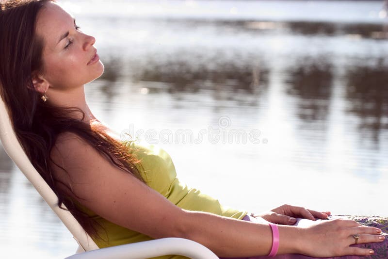 Attractive brunette relaxing on a deckchair. Attractive brunette relaxing on a deckchair.