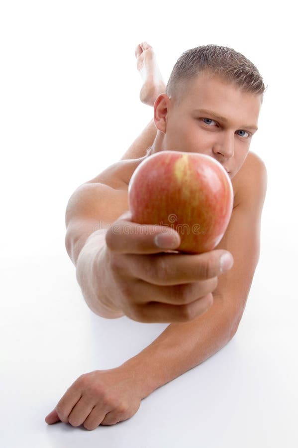 Laying fit guy showing apple on an isolated background. Laying fit guy showing apple on an isolated background