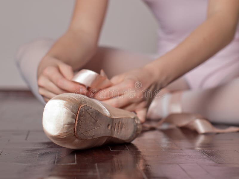 Sitting girl puts her pointe ballet shoes. Sitting girl puts her pointe ballet shoes