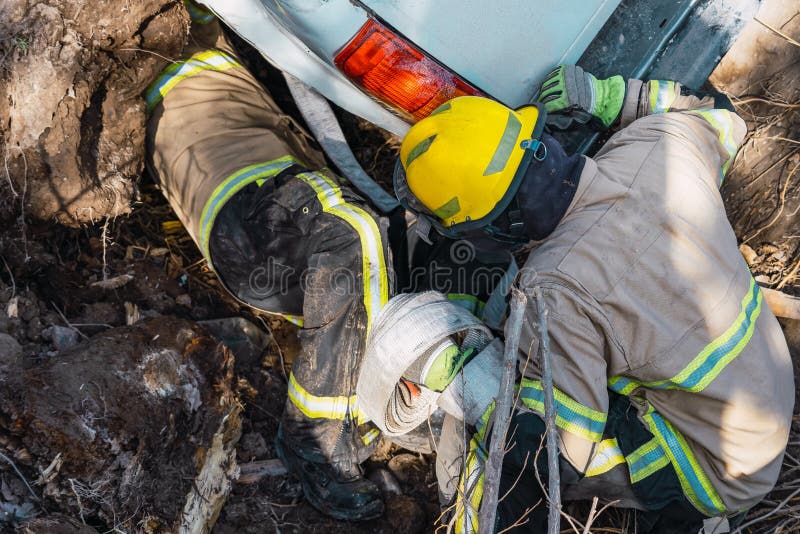 消防员正在营救掉入沟渠的汽车 库存照片