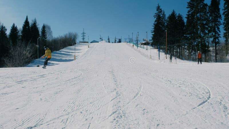 救生服的人沿着走在雪板倾斜的山在推力旁边