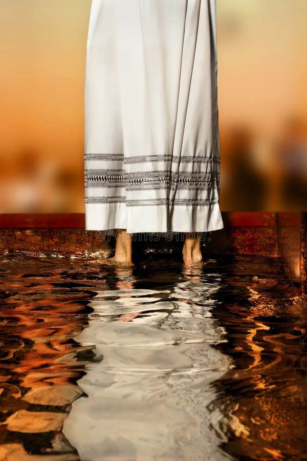 Priest's white robe reflecting in baptismal font water. Priest's white robe reflecting in baptismal font water