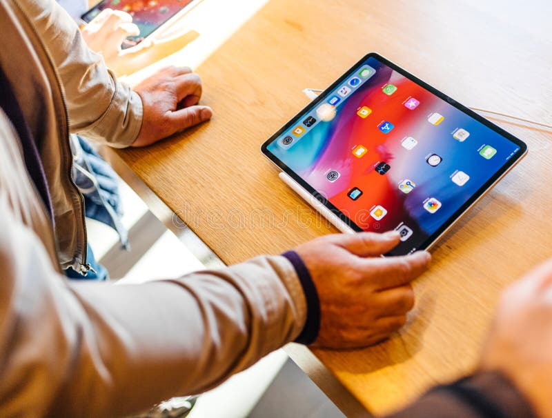 PARIS, FRANCE - NOV 7, 2018: Senior customer experiencing new Apple iPad Pro tablet with Face ID, Neural Engine and thin completely redesigned body - admiring the tablet. PARIS, FRANCE - NOV 7, 2018: Senior customer experiencing new Apple iPad Pro tablet with Face ID, Neural Engine and thin completely redesigned body - admiring the tablet