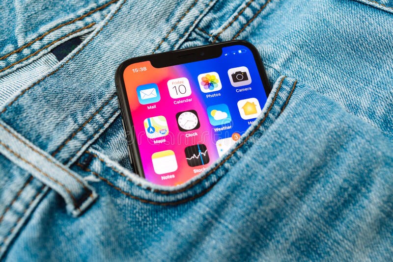 PARIS, FRANCE - NOV 10, 2017: New Apple iPhone X smartphone telephone mobile in pocket of fashion denim jeans pants trousers with home screen apps. PARIS, FRANCE - NOV 10, 2017: New Apple iPhone X smartphone telephone mobile in pocket of fashion denim jeans pants trousers with home screen apps