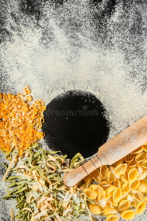 新鲜出炉的熟的面团，坐落在黑暗的表面上的粉尘用面粉. 意大利面食。. tagliatelle. 生的面食。. 意大利面食配方. 免版税库存照片