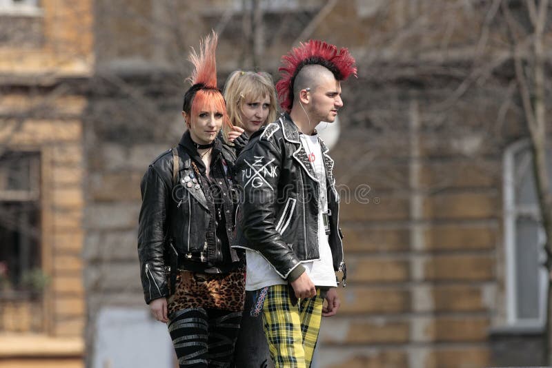 Punk fashion is the clothing, hairstyles, cosmetics, jewelry, and body modifications of the punk subculture. Contemporary street punks wear leather, denim, metal spikes or studs, chains and military-style boots. They often wear elements of early punk fashion, such as kutten vests, bondage trousers and torn clothing. There is a large influence by DIY-created and modified clothing, such as ripped or stitched-together trousers or shirts, or trousers that are tightly tapered. Jackets and vests often have patches or are painted with logos that express musical tastes or political views. Bullet belts and belts with metal studs are popular. Hair is often spiked and/or dyed in bright, unnatural colours and arranged into a mohawk or liberty spikes. Hair could also be cut very short or shaved. Punk fashion is the clothing, hairstyles, cosmetics, jewelry, and body modifications of the punk subculture. Contemporary street punks wear leather, denim, metal spikes or studs, chains and military-style boots. They often wear elements of early punk fashion, such as kutten vests, bondage trousers and torn clothing. There is a large influence by DIY-created and modified clothing, such as ripped or stitched-together trousers or shirts, or trousers that are tightly tapered. Jackets and vests often have patches or are painted with logos that express musical tastes or political views. Bullet belts and belts with metal studs are popular. Hair is often spiked and/or dyed in bright, unnatural colours and arranged into a mohawk or liberty spikes. Hair could also be cut very short or shaved.