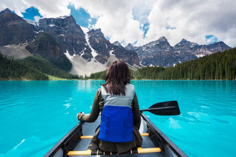Tourist canoeing on Moraine Lake in Banff National Park, Alberta, Canada. Canadian Rockies natural landmark, glacial lake surrounded by mountains. Tourist canoeing on Moraine Lake in Banff National Park, Alberta, Canada. Canadian Rockies natural landmark, glacial lake surrounded by mountains.