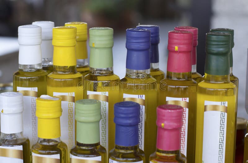 Glass olive oil bottles without trademark with colorful sealed stoppers and greek ornament on blurred background closeup. Glass olive oil bottles without trademark with colorful sealed stoppers and greek ornament on blurred background closeup