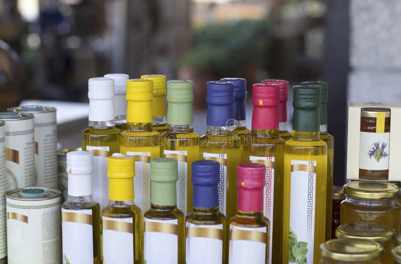 Glass olive oil bottles without trademark with colorful sealed stoppers and greek ornament on blurred background. Glass olive oil bottles without trademark with colorful sealed stoppers and greek ornament on blurred background