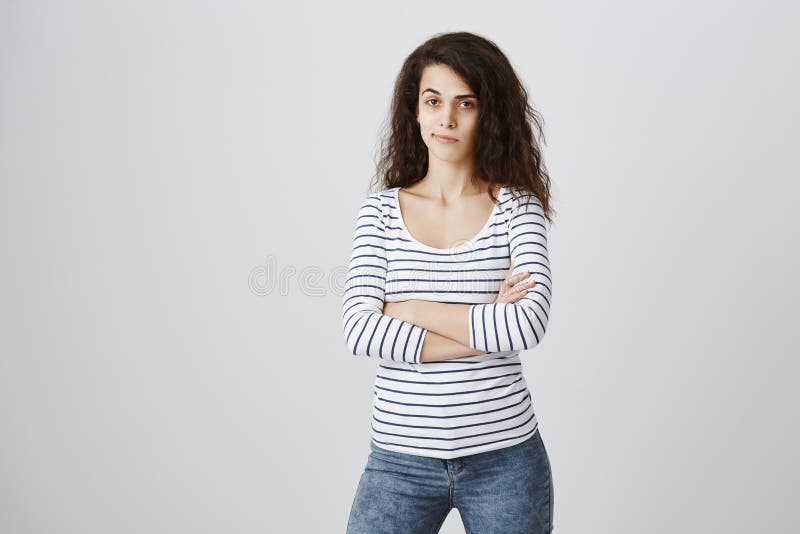 是嫉妒的女朋友可疑的 站立用横渡的手的美丽的卷发的白种人女孩室内射击 免版税库存照片 是嫉妒的女朋友可疑的 站立用横渡的手的美丽的卷发的白种人女孩室内射击 免版税库存照片