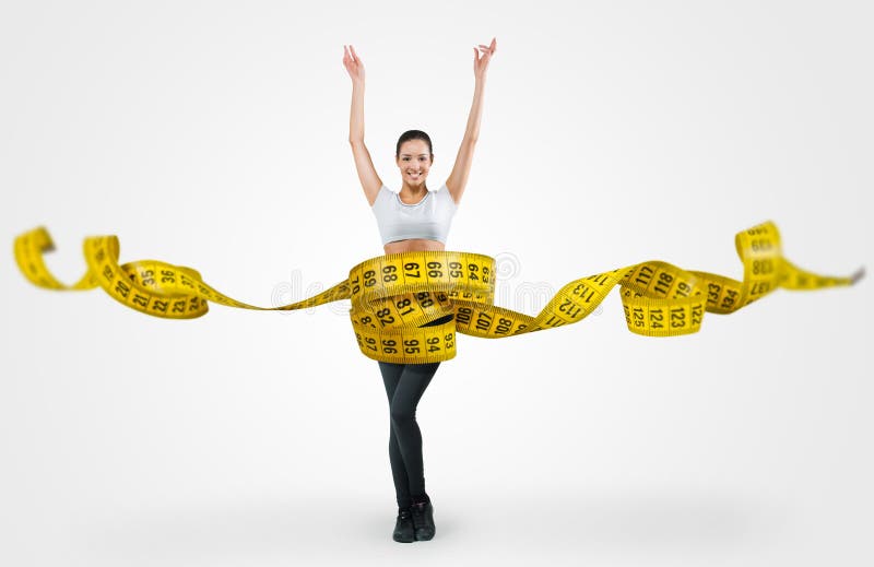 Fit young woman with a large measuring tape on gray background. Fit young woman with a large measuring tape on gray background