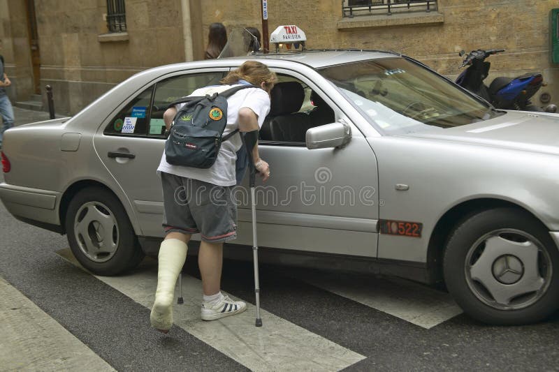 有下垂在出租汽车，巴黎，法国下的断腿的男子大学生