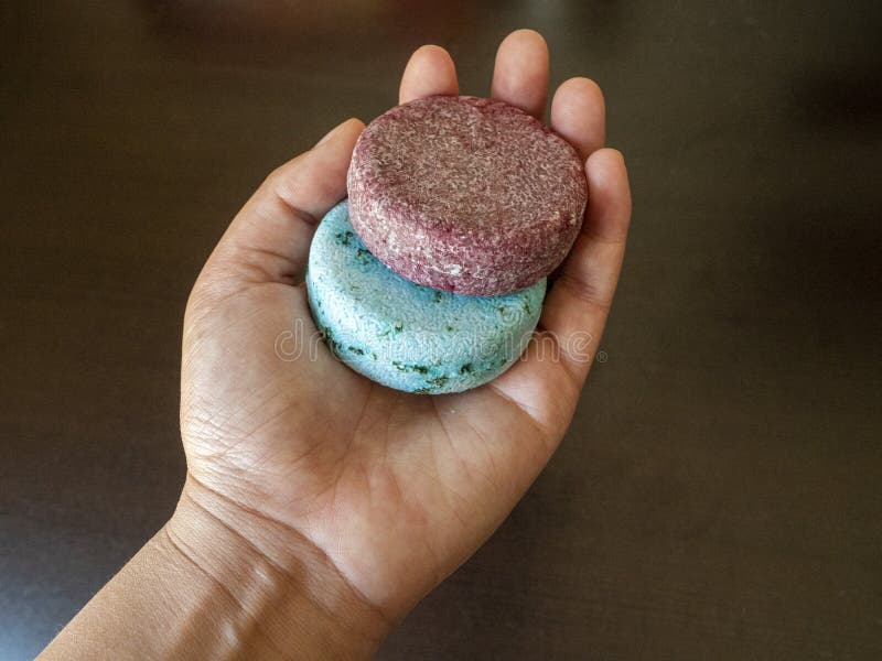 Hand holding two red and blue Shampoo bars before washing their hair in the shower  version 2. Hand holding two red and blue Shampoo bars before washing their hair in the shower  version 2