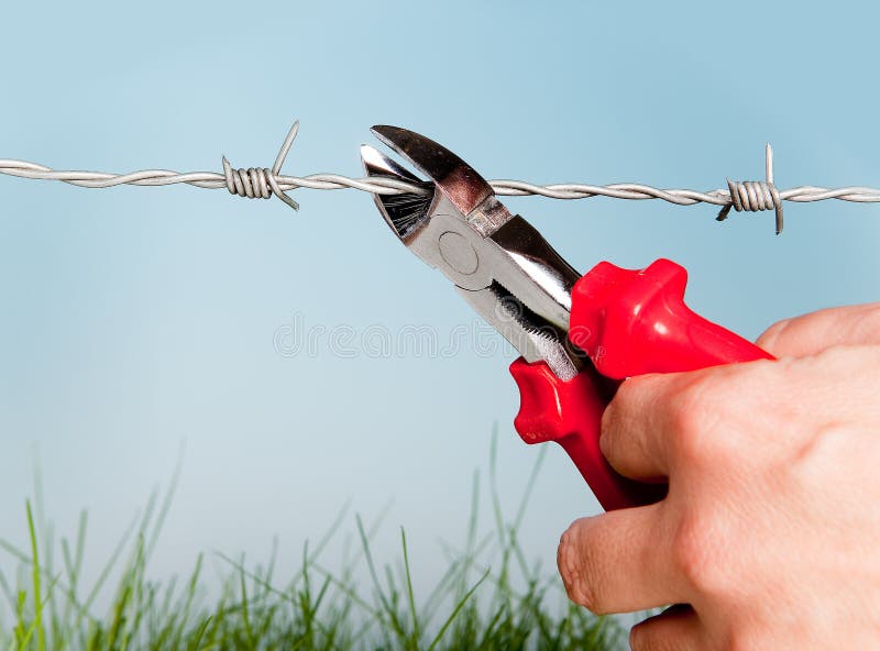 Hand cutting barbed wire to escape for freedom. Hand cutting barbed wire to escape for freedom