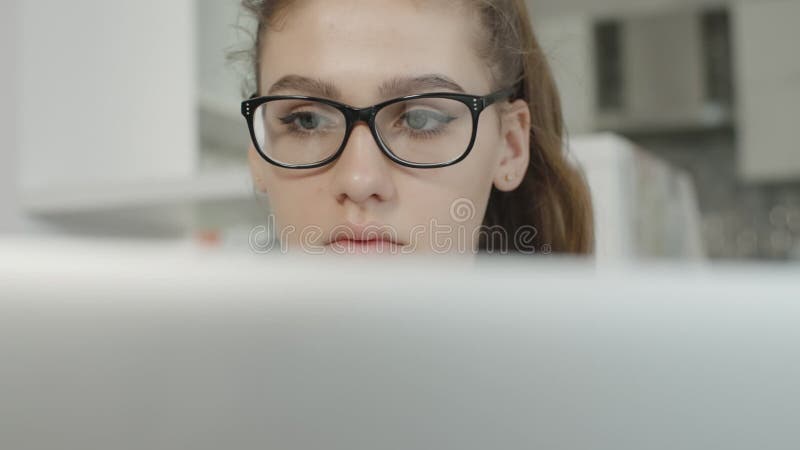 有困惑的神色的十几岁的女孩在膝上型计算机读了文本，看笔记本屏幕，为检查做准备