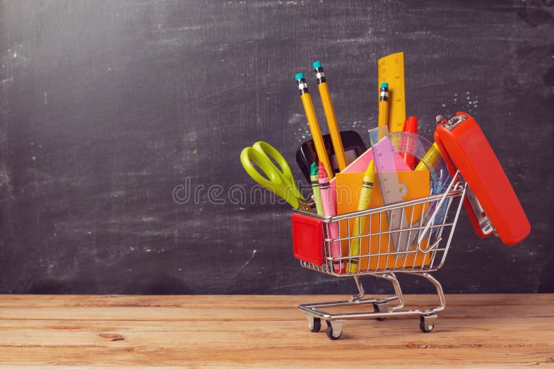 有学校用品的购物车在黑板背景 回到学校销售额概念 库存图片