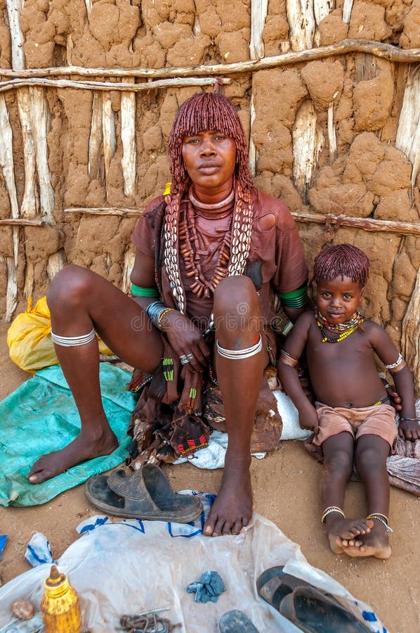 TURMI, ETHIOPIA - MARCH 17,2014 - Hamar woman with child Maki(2).Women weave your hair into small braids and painted them red-colored clay. The Hamar are an Omotic community inhabiting southwestern Ethiopia. TURMI, ETHIOPIA - MARCH 17,2014 - Hamar woman with child Maki(2).Women weave your hair into small braids and painted them red-colored clay. The Hamar are an Omotic community inhabiting southwestern Ethiopia.