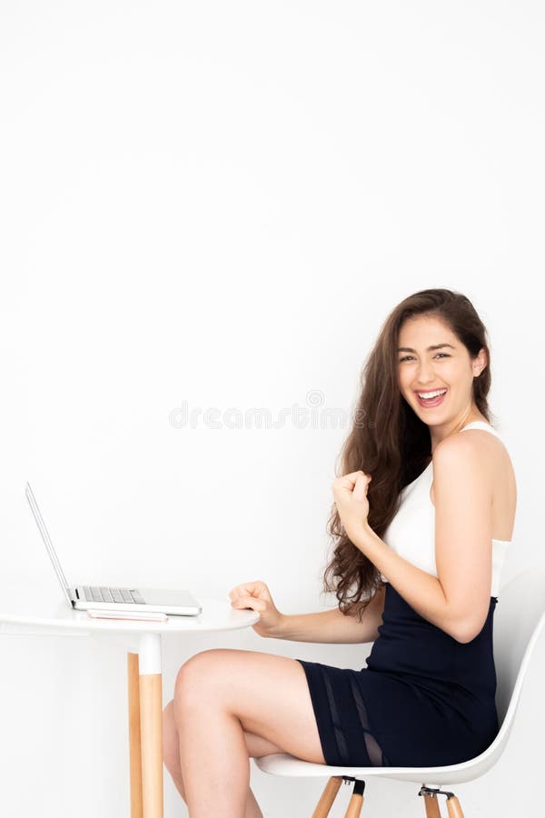 有成就的成功和极端愉快的年轻白种人女商人激发并且取得了坐与膝上型计算机的胜利