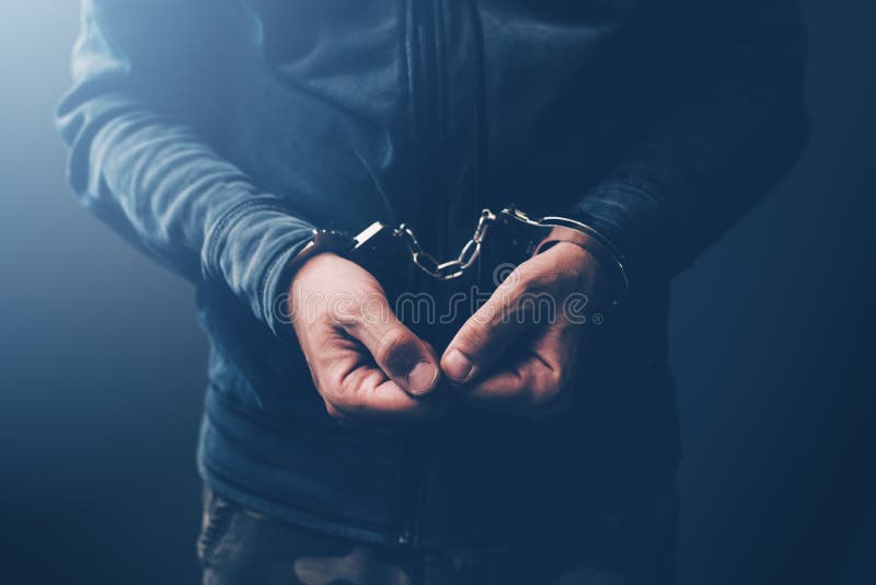 Arrested computer hacker and cyber criminal with handcuffs, close up of hands. Arrested computer hacker and cyber criminal with handcuffs, close up of hands