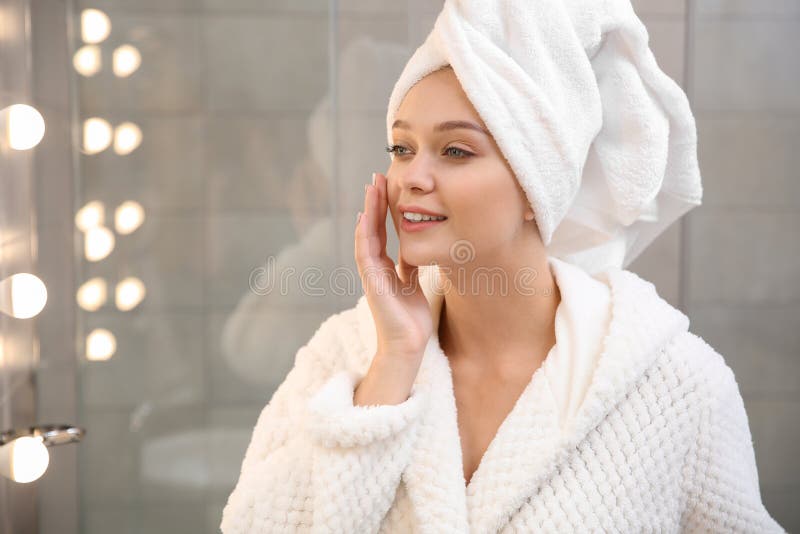 头部戴着毛巾的漂亮女人在镜子附近 免版税图库摄影