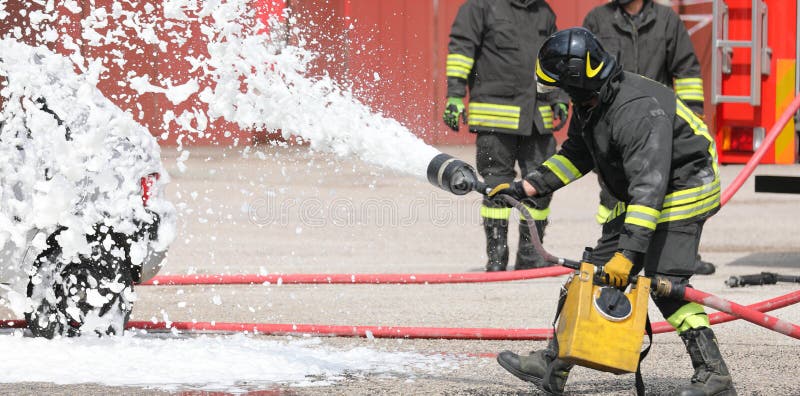 team of firefighters extinguishing with foam the car after road accident. team of firefighters extinguishing with foam the car after road accident