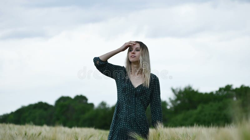 有湿头发的走在自然的雨中的一个愉快的可爱的白种人金发碧眼的女人的画象 室外麦田