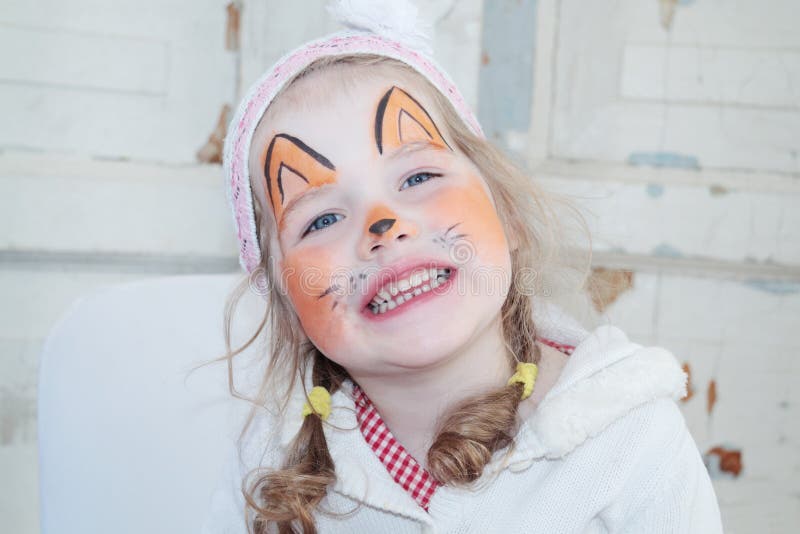 Little beautiful girl with face painting of fox unnatural smiles. Little beautiful girl with face painting of fox unnatural smiles