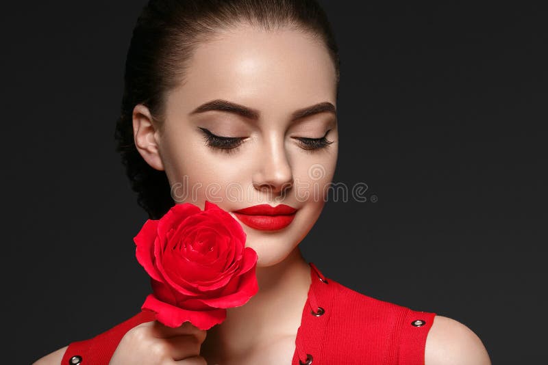 有玫瑰色花美丽的卷发和嘴唇的秀丽妇女