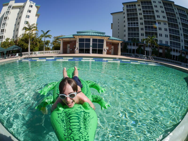 A fisheye view of a boy having fun with an inflatable alligator at a resort swimming pool in Fort Myers Florida. A fisheye view of a boy having fun with an inflatable alligator at a resort swimming pool in Fort Myers Florida.