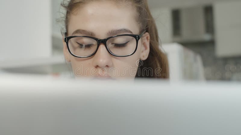 有疲乏的神色的女孩在膝上型计算机读了文本，看笔记本屏幕，为检查做准备