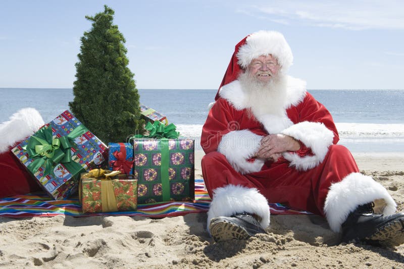 Happy Santa Claus with presents and Christmas tree relaxing on beach. Happy Santa Claus with presents and Christmas tree relaxing on beach