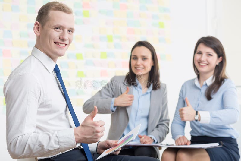Happy young businesspeople in corporation with positive attitude. Smiling and showing thumbs up. Happy young businesspeople in corporation with positive attitude. Smiling and showing thumbs up