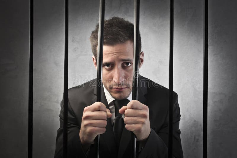 Sad young businessman behind bars. Sad young businessman behind bars