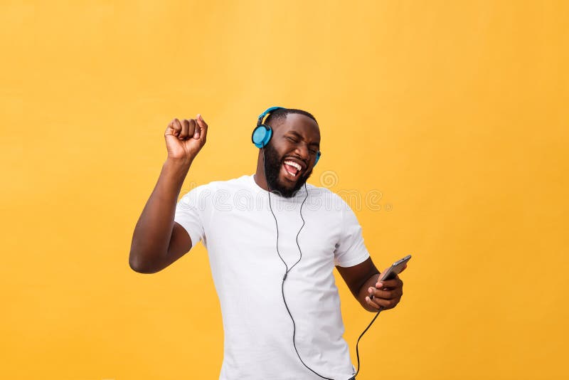 African American man with headphones listen and dance with music. Isolated on yellow background. African American man with headphones listen and dance with music. Isolated on yellow background.