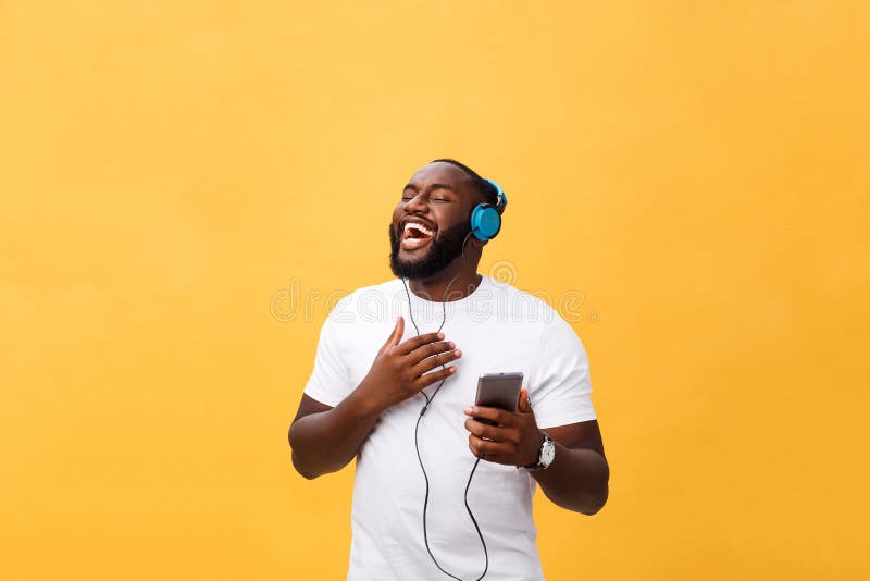 African American man with headphones listen and dance with music. Isolated on yellow background. African American man with headphones listen and dance with music. Isolated on yellow background.