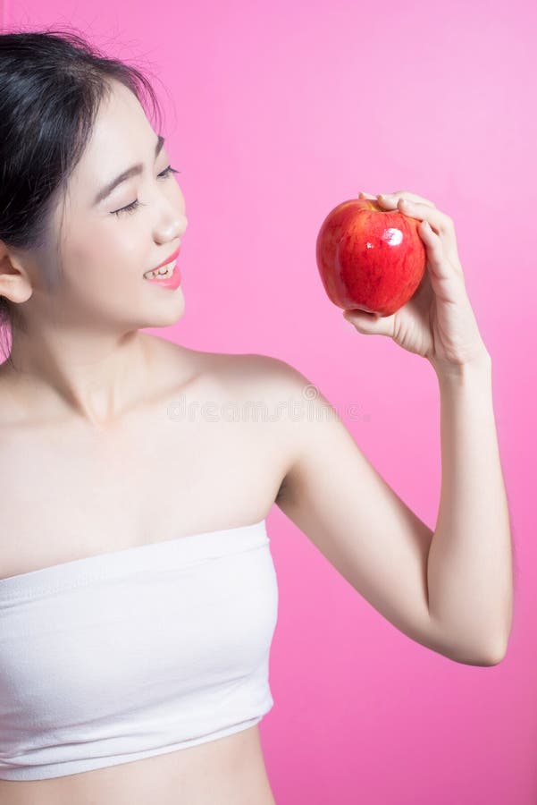 有苹果概念的亚裔妇女 微笑和拿着苹果的她 秀丽面孔和自然构成 隔绝在桃红色背景 库存图片 有苹果概念的亚裔妇女 微笑和拿着苹果的她 秀丽面孔和自然构成 隔绝在桃红色背景 库存图片