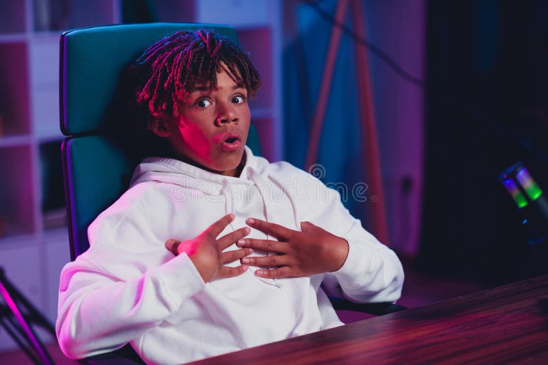 幽默的游戏玩家在家中用动态霓虹灯光进行直播，在沉浸式内容中表现出投入和富有表现力 免版税库存图片