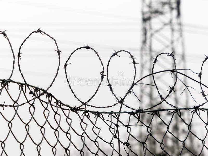 A fence is secured with barbed wire. symbolic photo for security, prison and crime. A fence is secured with barbed wire. symbolic photo for security, prison and crime.