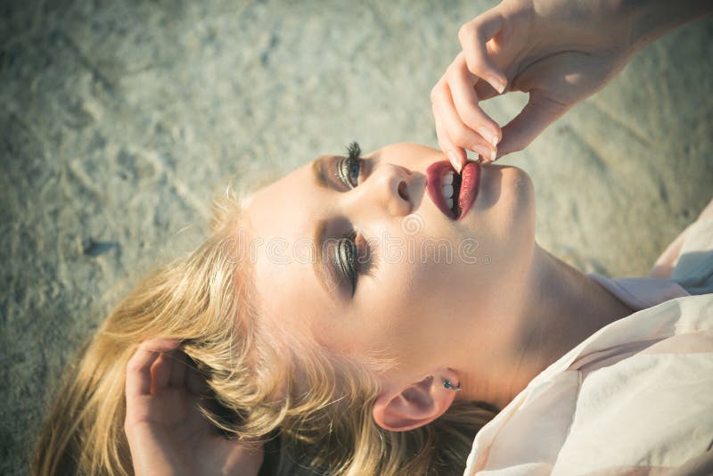 Girl with long blond healthy hair lie on concrete surface. Sensual woman with red sexy lips on makeup face outdoor. Skincare, skin, make up. Beauty, look concept. Haircare, health, hairstyle. Girl with long blond healthy hair lie on concrete surface. Sensual woman with red sexy lips on makeup face outdoor. Skincare, skin, make up. Beauty, look concept. Haircare, health, hairstyle.